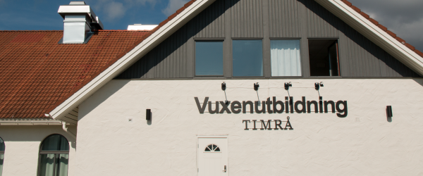 En vitt hus med brunt tak. Ovanför dörren på huset står det Vuxenutbildning Timrå.