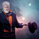 Bilden föreställer Ronny Eriksson som står ute i naturen och håller i en rutig hatt