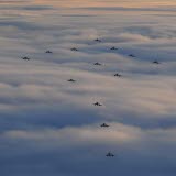 Bilden föreställer flera flygplan ovanför molnen
