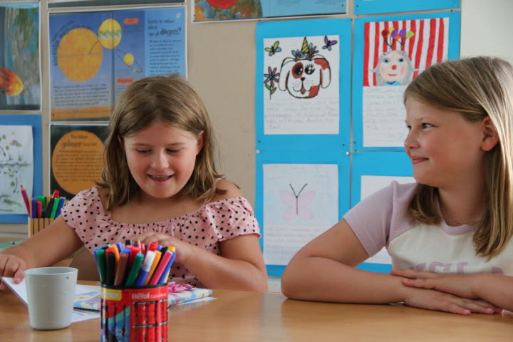 Två tjejer som ser väldigt glad ut i klassrummet.