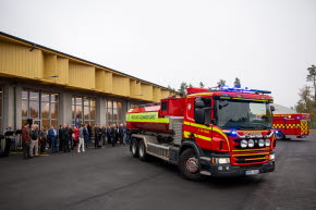 Nya räddningsstationen i bakgrunden, en grupp med människor är samlade framför byggnaden. Längst fram syns en brandbil med blåljus igång.