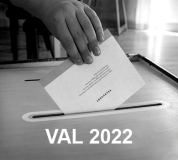 En svartvit bild där en hand lägger ner ett röstkort i en trälåda. På bilden ser man texten val 2022