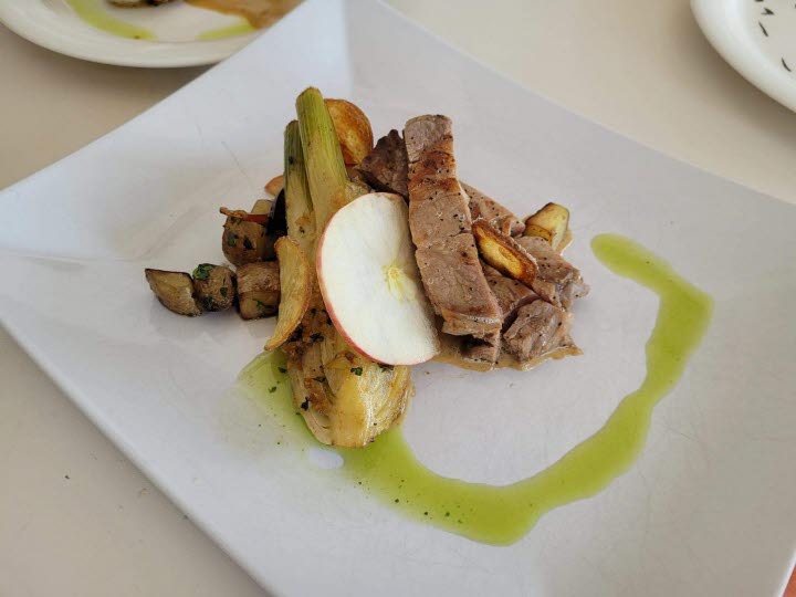 En maträtt på en vit tallrik. På tallriken syns potatis, fläskkaré och glaze. 