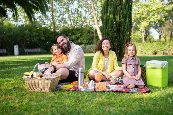Bilden föreställer en familj som sitter och fikar på en gräsmatta
