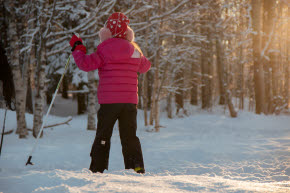 Ett barn i rosa jacka åker längdskidor
