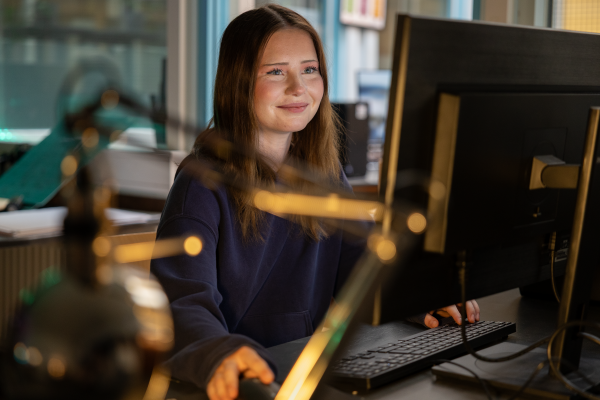 En elev sitter vid en dator. Hon är glad.