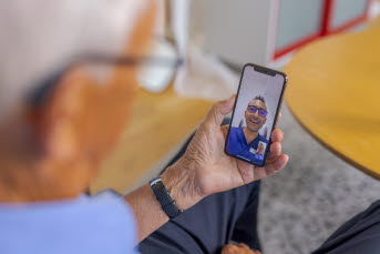 En äldre man har ett digitalt läkarsamtal på sin mobiltelefon