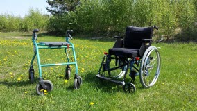En rollator och en rullstol står på en gräsmatta.