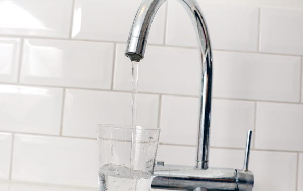 Bilden föreställer en vattenkran som det rinner vatten ur till ett glas.