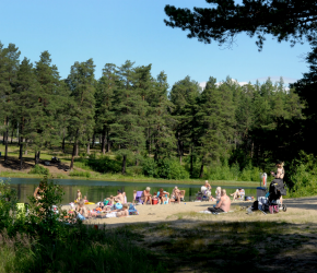 Människor sitter på en strand längs med vattnet.