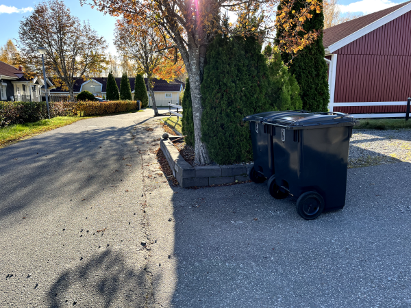 Två svarta soptunnor utanför en villa