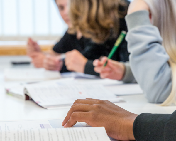 Personer sitter vid ett bord och studerar.