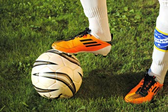 En person med fotbollsskor med sin fot på en fotboll.