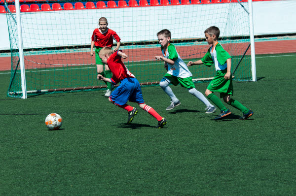 Fyra pojkar spelar fotboll på en fotbollsplan.