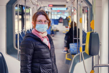 Kvinna med munskydd åker buss.