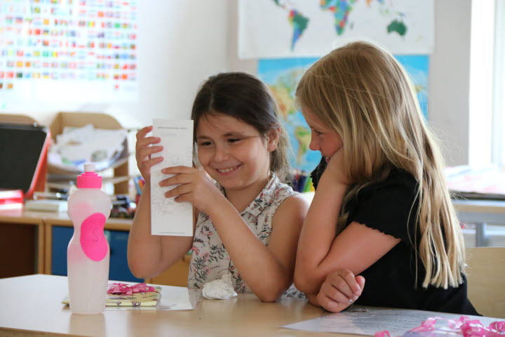 Två elever i klass 2b tittar på ett papper och skrattar.