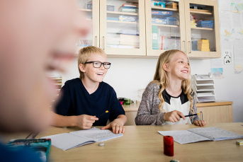 Två elever sitter i ett klassrum vid ett bord.