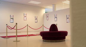 Väggarna i bibliotekets konsthörna pryds av dikter. En röd matta är utlagd.