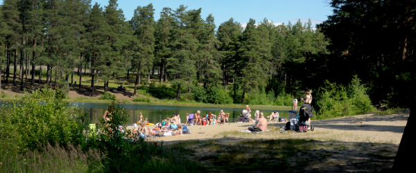 Människor sitter på en strand längs med vattnet.