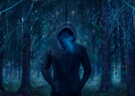 Bilden föreställer en mörkklädd man i en skog