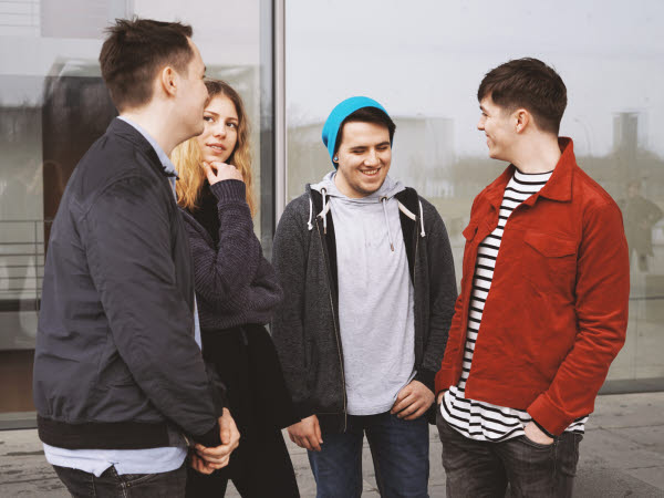 En grupp med fyra tonåringar står tillsammans och skrattar