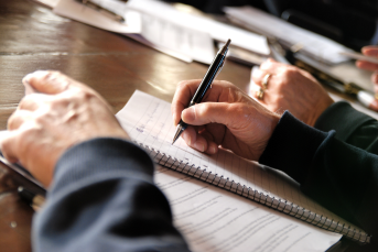 Bilden föreställer en hand som skriver i ett block.