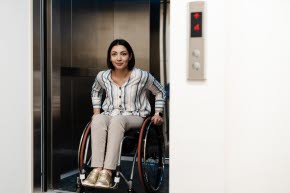 En kvinna sitter i en rullstol inuti en hiss