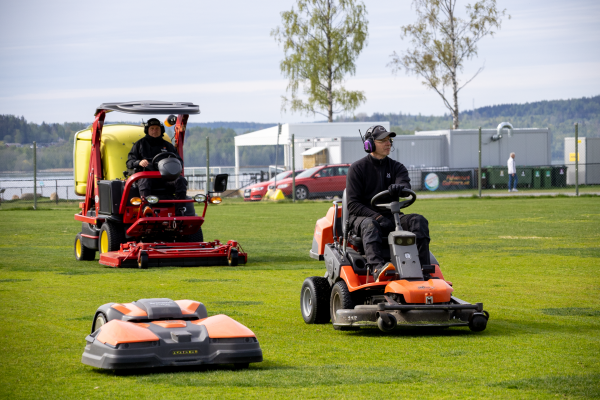 Två personer klipper gräs på Fagerviksfältet