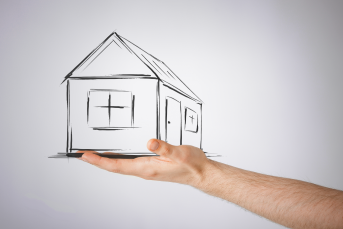 Bilden föreställer en hand som håller i ett ritat hus