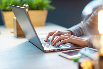 En person skriver på en laptop.