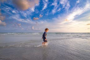 En strand med en pojke som springer i vattnet.