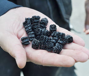 Ett femtontal svarta små platsbitar hålls i en öppen hand