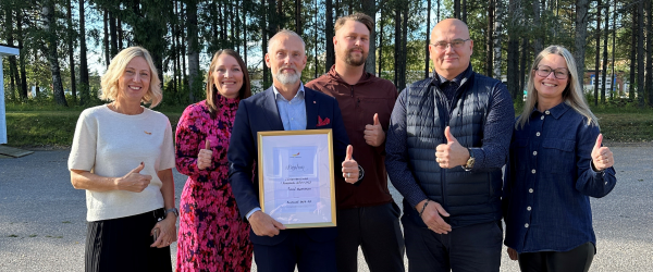 Sex personer står utomhus. De är glada över att ha fått utmärkelsen Norrlands Bästa Företagsklimat.