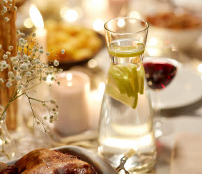 Dukat bord med vattenkaraff, rostad kyckling och en vas med stjärngräs.