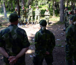 Militärklädda människor i skogen.