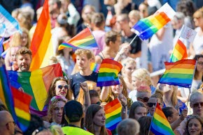 Pridefestival med folk som viftar prideflaggor.