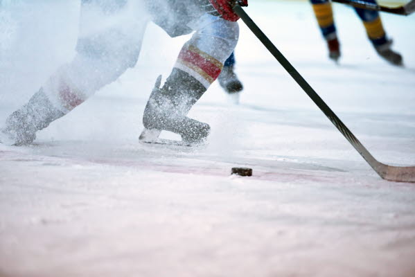 Bilden föreställer hockeyspelare med klubba och puck på is
