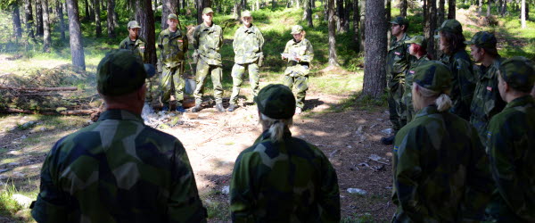 Militärklädda människor i skogen.