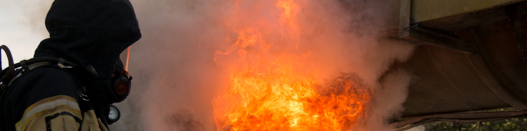 En elev med skyddskläder och brandsläckare, släcker en flammande eld.