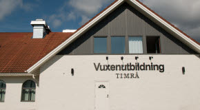 En vitt hus med brunt tak. Ovanför dörren på huset står det Vuxenutbildning Timrå.