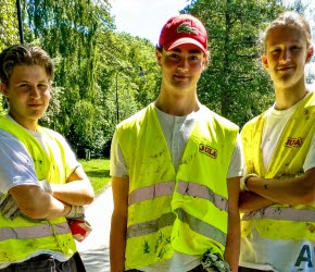 Tre yngre killar som står med arbetskläder utomhus