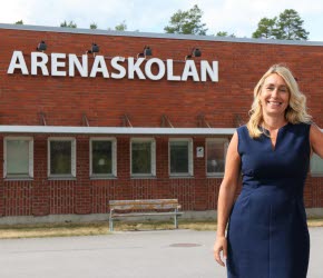 Rektor Annelie Granö-Sörell står framför Arenaskolan och ler mot kameran.