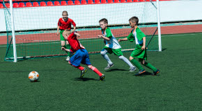 Fyra pojkar spelar fotboll på en fotbollsplan.