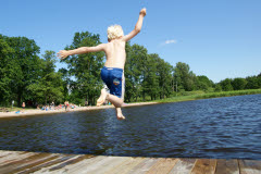Pojke hoppar från brygga i vattnet