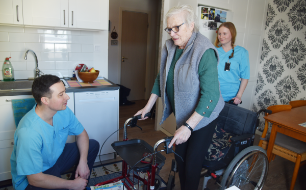 Andreas Silverhav hjälper Birgitta Jonsson att träna vid rullstolen
