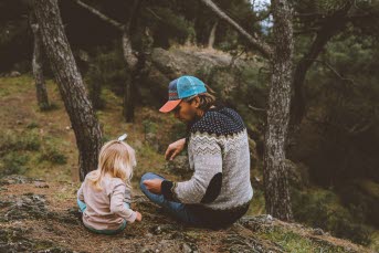 En pappa och hans dotter sitter på en klippa i skogen
