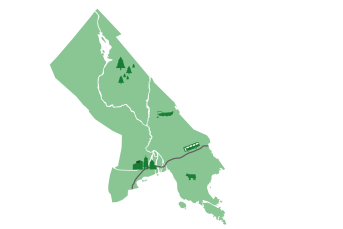 Karta över en kommun indelad i olika områden med symboler: skog och träd i norr, jordbruk med ko i söder, samt stad, väg och tåg i mitten. En flod eller vattendrag rinner genom kartan från norr till söder.