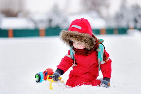 Bild på ett barn som leker med en traktor i snön.