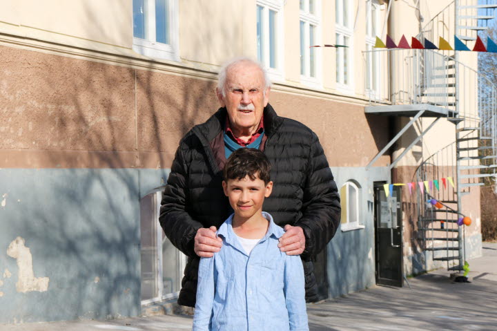 Olle, föredetta elev på Fagervik skola, står tillsammans med sitt barnbarnsbarn Alfons framför skolan.
